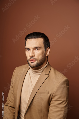 portrait of attractive man in elegant attire looking at camera on beige backdrop, handsome executive © LIGHTFIELD STUDIOS