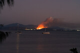 A fire is burning on the shore of a lake