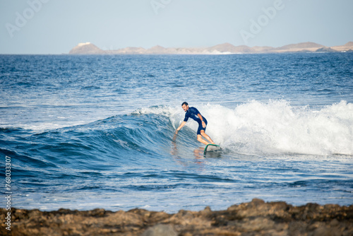 Front View of Surfer Riding a Wave Touching the Water with the Hand in a Sunny Day.Copy Space