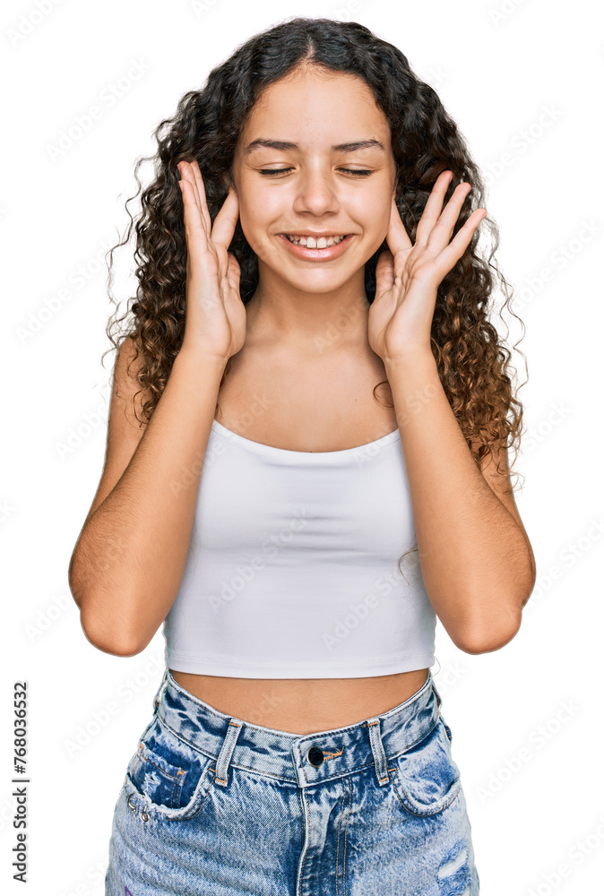 Teenager hispanic girl wearing casual clothes covering ears with fingers with annoyed expression for the noise of loud music. deaf concept. Teenager hispanic girl wearing casual clothes covering ears with fingers with annoyed expression for the noise of loud music. deaf concept.