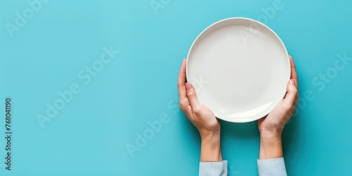 hand holding plate on blue background copy space top view 