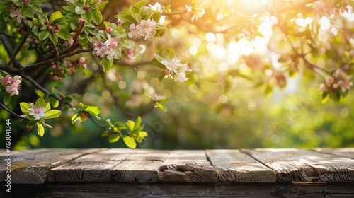 Beautiful spring background with young green leaves and flowering branches with empty wooden table on outdoor nature.