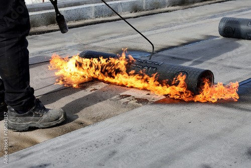 Valokuva Professional construction workers using a blowtorch to glue modified bitumen roll sheet over a concrete road