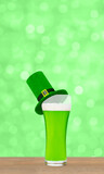 Glass of green beer with leprechauns green top hat on green blurred background. Saint Patrick's Day Concept. Empty space for text