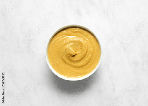 Mustard sauce in bowl on white marble table, flat lay, top view