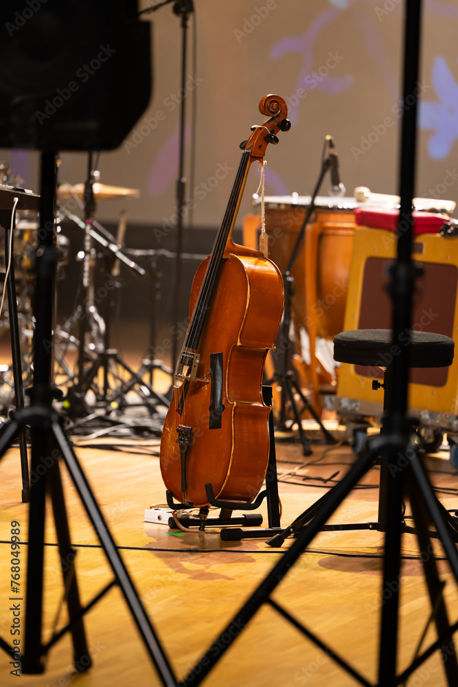 Cello on a stand placed on the stage. Photo taken with artificial light in the concert hall during a break in the concert