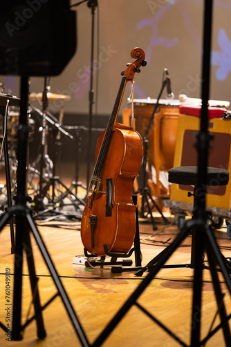 Cello on a stand placed on the stage. Photo taken with artificial light in the concert hall during a break in the concert