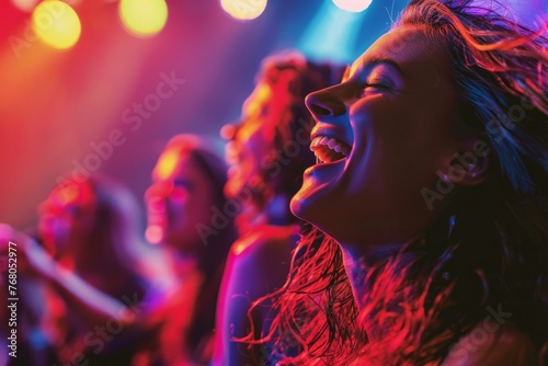 A woman passionately sings into a microphone during a lively concert, surrounded by a crowd of enthusiastic fans