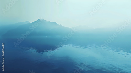 This is a beautiful landscape image of a lake and mountains in the distance. The water is a deep blue color and the sky is foggy.