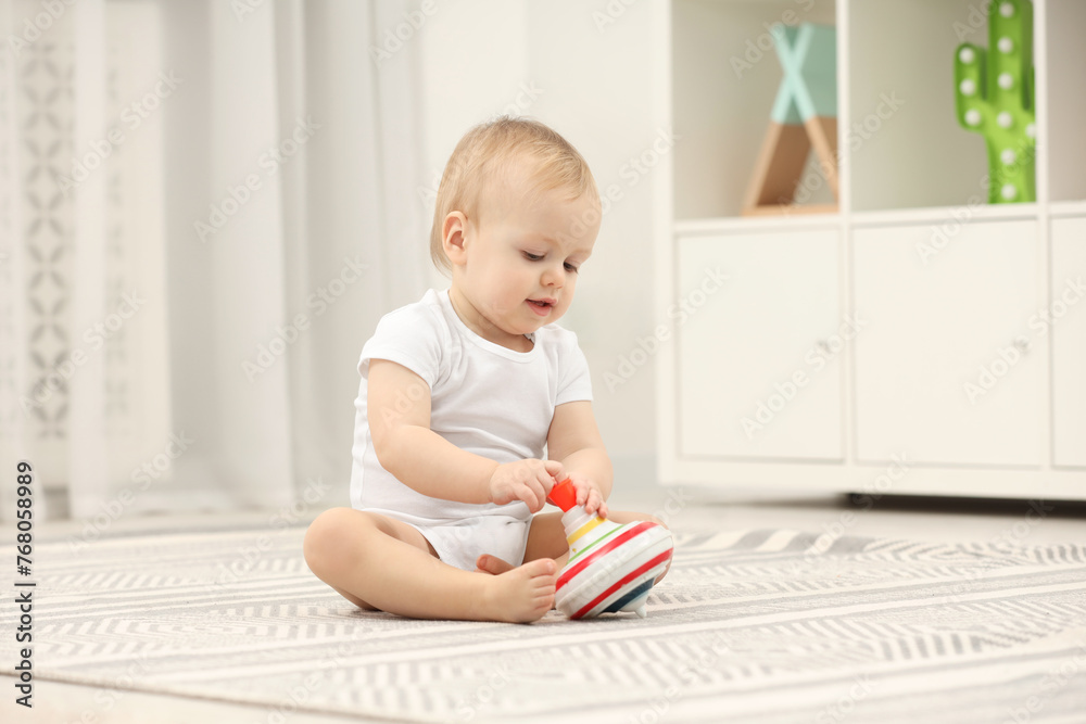 Children toys. Cute little boy playing with spinning top on rug at home Children toys. Cute little boy playing with spinning top on rug at home