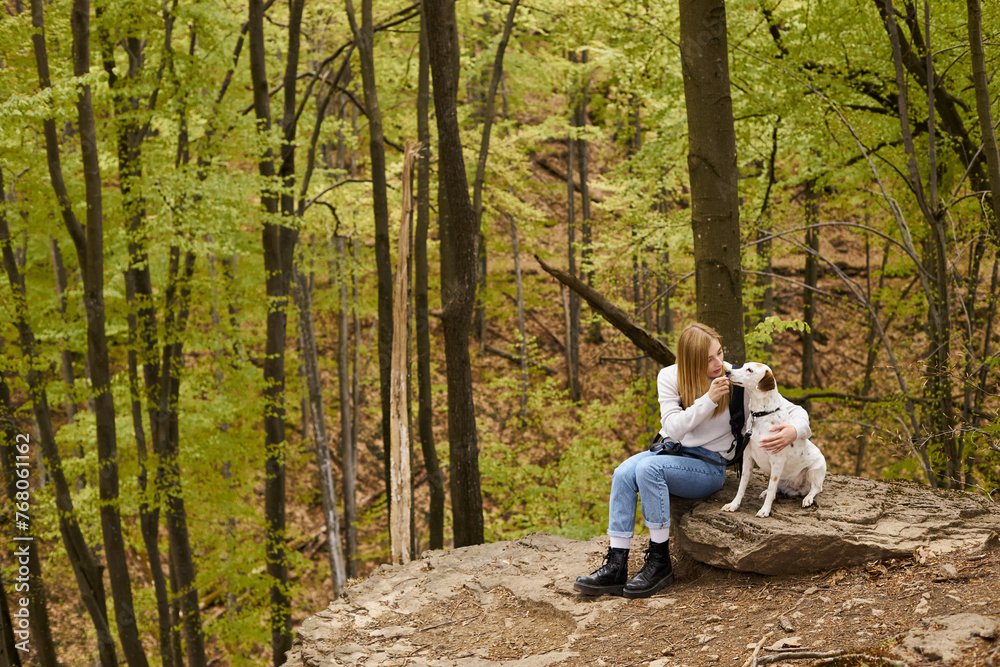 Fototapeta premium Tender blonde woman and her dog hugging in forest, bonding while sitting at rest stop