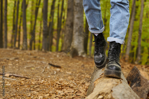 Cropped photo of female legs in hiking boots making a step on a wood in forest scenery