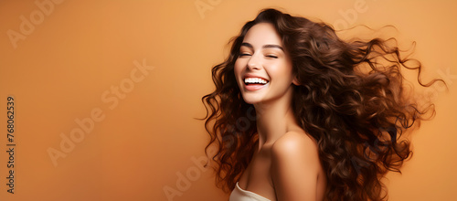 Joyful laughing woman with long curly hair, brunette model against solid background with copy space, panoramic banner