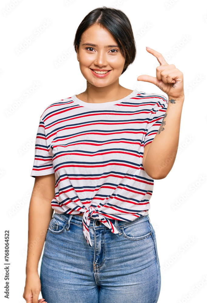 Beautiful young woman with short hair wearing casual clothes smiling and confident gesturing with hand doing small size sign with fingers looking and the camera. measure concept. Beautiful young woman with short hair wearing casual clothes smiling and confident gesturing with hand doing small size sign with fingers looking and the camera. measure concept.