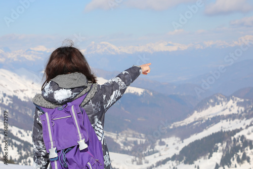 girl hiker during the trip  in winter with the purple backpack on her shoulders points to a point on the horizon