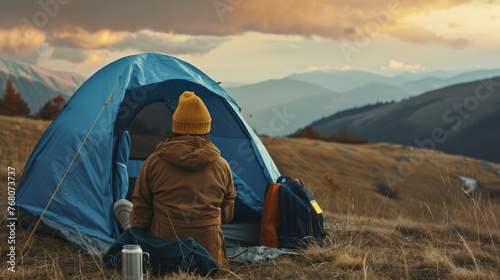 Person Next to Blue Tent Overlooking Mountainous Landscape at Dusk