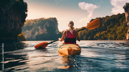Back view shot of young woman tourist paddling on kayaking on beautiful lake in sunny day on natural mountains backgrounds, Active lifestyle, active water sports, spring summer outdoor activities.