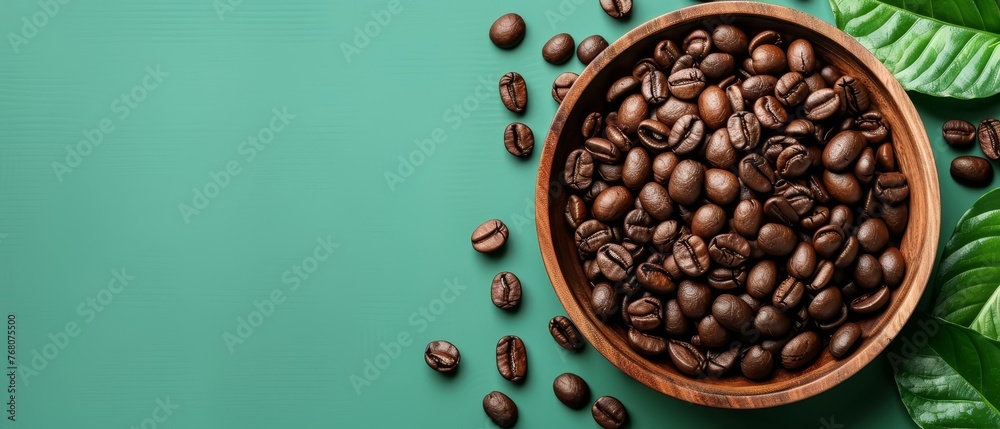 A bowl of coffee beans surrounded by green leaves on a blue background Space in the middle A bowl of coffee beans surrounded by green leaves on a blue background Space in the middle
