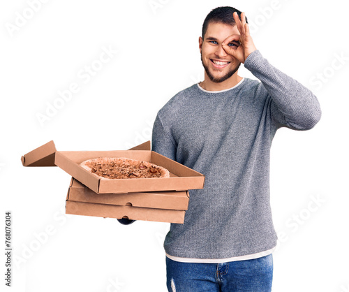 Young handsome man holding delivery italian pizza boxes smiling happy doing ok sign with hand on eye looking through fingers photo