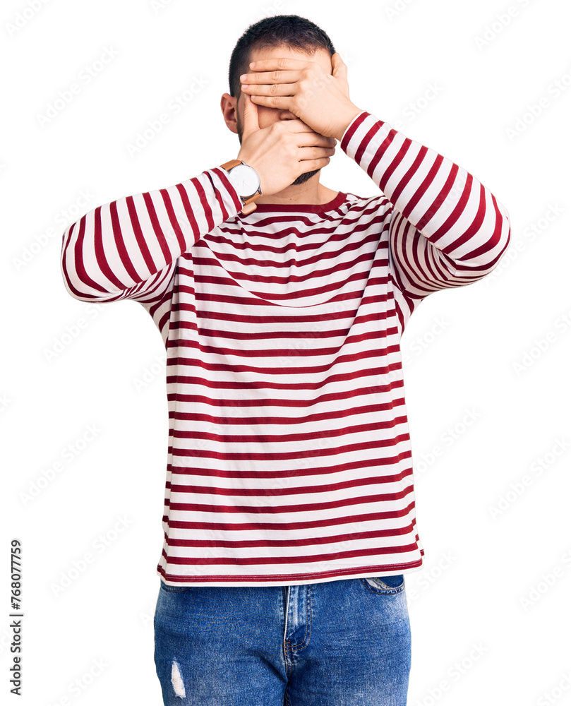 Φωτογραφία Young handsome man wearing striped sweater covering eyes and mouth with hands, surprised and shocked