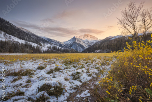 A panoramic winter landscape of snow-capped mountains painted by a fiery sunset against a backdrop of pink and purple clouds