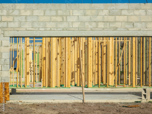 Parallel pattern of vertical wooden studs to support future walls inside the concrete shell of a single-family house under construction on a sunny morning in southwest Florida photo