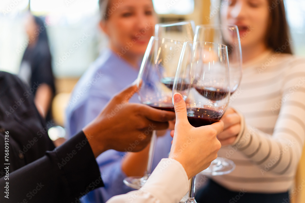 Group of diverse ethnicity people enjoy testing red wine together.