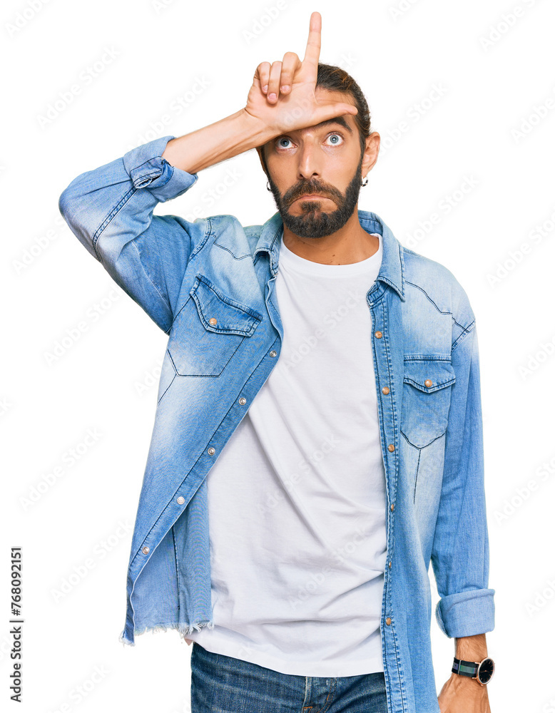 Attractive man with long hair and beard wearing casual denim jacket making fun of people with fingers on forehead doing loser gesture mocking and insulting. Attractive man with long hair and beard wearing casual denim jacket making fun of people with fingers on forehead doing loser gesture mocking and insulting.