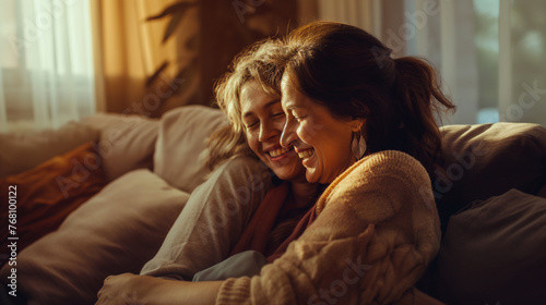 A mother and her adult daughter wrapped in a heartfelt hug on the living room sofa, sharing smiles and laughter, the soft afternoon sunlight filtering through the curtains and cast