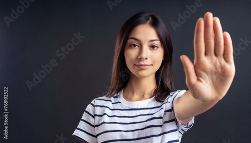 Close up of woman showing stop gesture with hand raising up on black background, young female protesting against domestic violence and abuse, bullying, saying no to gender discrimination photo