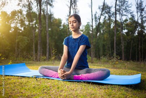 indian slim women practicing baddha konasana or cobbler pose or butterfly pose yoga in the calm nature during sunrise
