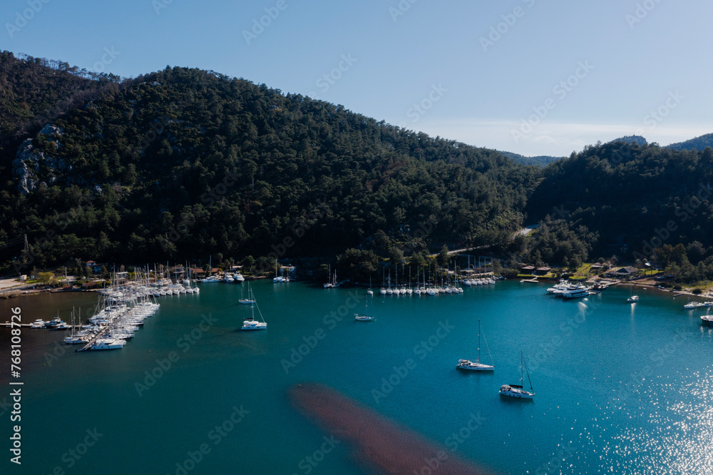 Aerial view of boats and beautiful city in Marmaris, Turkey. Landscape with boats in marina bay, sea, city lights, mountains. Top view from drone. 