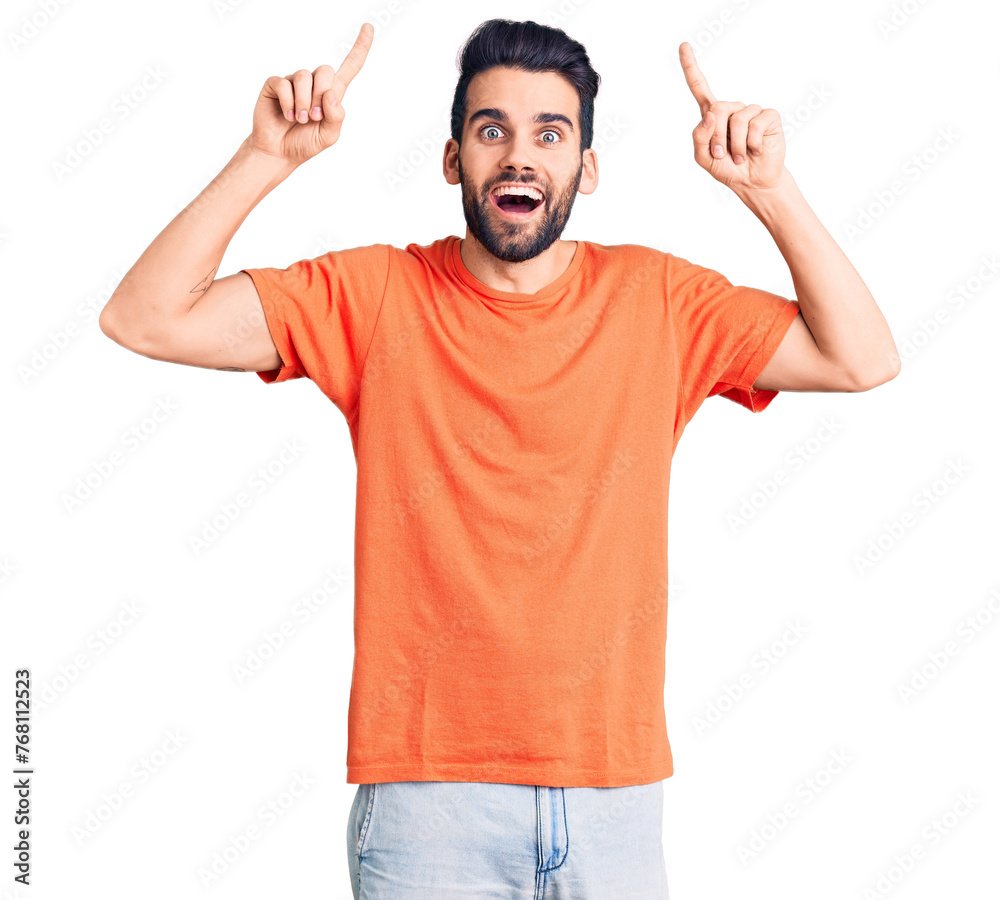 Young handsome man with beard wearing casual t-shirt smiling amazed and surprised and pointing up with fingers and raised arms. Young handsome man with beard wearing casual t-shirt smiling amazed and surprised and pointing up with fingers and raised arms.