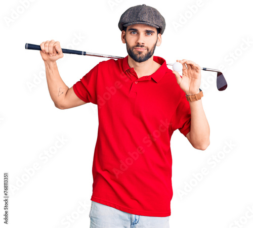 Young handsome man with beard playing golf holding club and ball thinking attitude and sober expression looking self confident