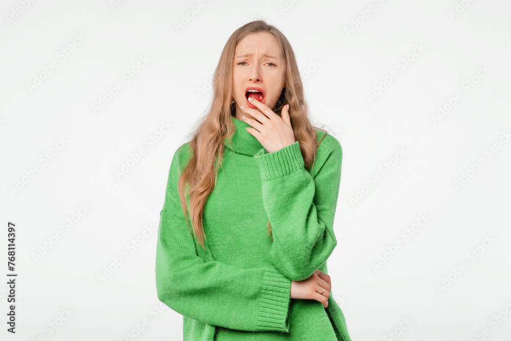Portrait of tired female looks sleepy, yawns, covers mouth with hand, worked all night. Blonde young woman feels exhaustion, standing over white studio backdrop Portrait of tired female looks sleepy, yawns, covers mouth with hand, worked all night. Blonde young woman feels exhaustion, standing over white studio backdrop