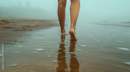 Woman walking on beach in foggy morning