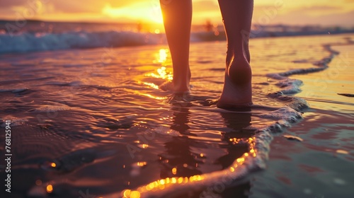 Woman's feet in the sea waves while walking on beach at sunset, romantic backgrounds with copy space.
