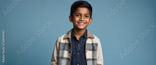 Cheerful Young Indian Boy Smiling with Confidence, against a blue background, exuding positivity and youth.