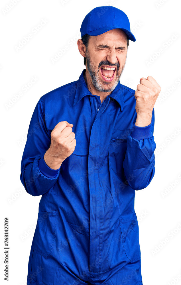 Middle age handsome man wearing mechanic uniform celebrating surprised and amazed for success with arms raised and eyes closed. winner concept. Middle age handsome man wearing mechanic uniform celebrating surprised and amazed for success with arms raised and eyes closed. winner concept.