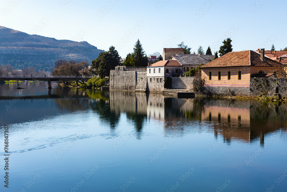 Old Town of Trebinje. Calm river reflects the buildings, showcasing minimalism with vivid blue waters and pastel building hues. Bosnia and Herzegovina
