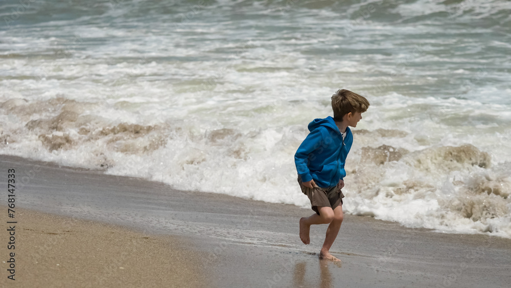 Little funny kid playing barefoot with the sea waves on the beach Little funny kid playing barefoot with the sea waves on the beach