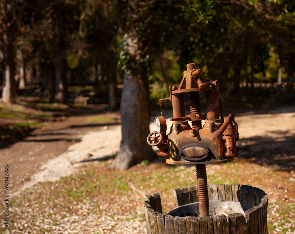 Old rusty hydraulic grape press in an overgrown field in Italy