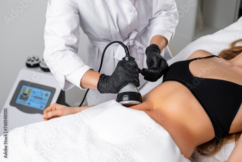Obraz na płótnie Engaging in ultrasound cavitation therapy for body contouring and anti cellulite treatment, a young woman benefits from hardware cosmetology techniques aimed at sculpting her body. w salonie