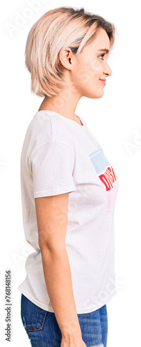 Young beautiful blonde woman wearing t shirt with diversity word message looking to side, relax profile pose with natural face with confident smile.