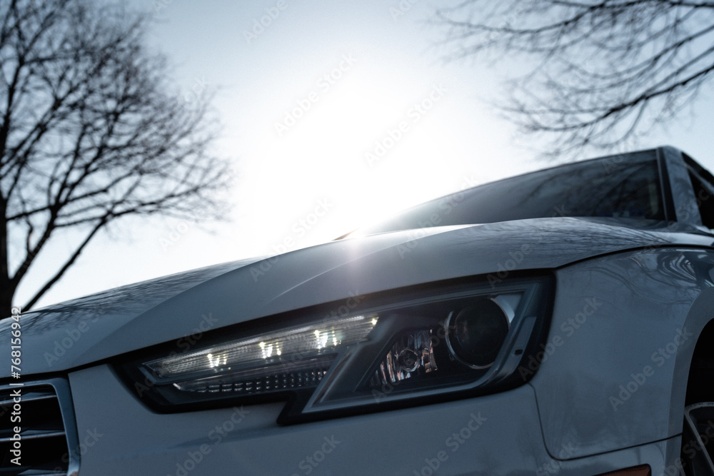 close up of a car front end with sunburst in background close up of a car front end with sunburst in background