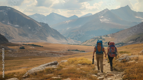 A hiker couple explores the wilderness hand in hand, amidst the majestic beauty of the mountains.
