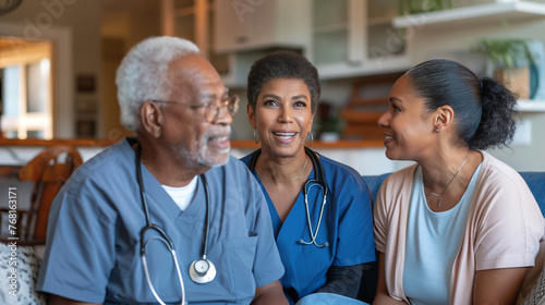 A below view captures a young healthcare worker engaged in conversation with a mature couple in the comfort of their home, conveying a sense of trust. photo