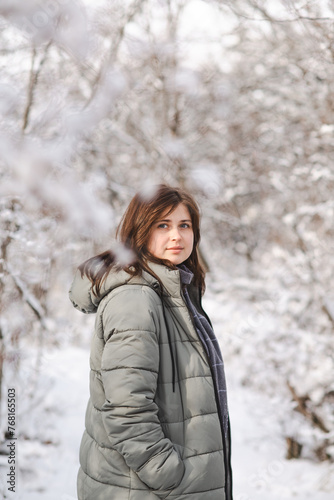 pretty young woman in winter clothes among trees covered with snow, girl walking in snowy forest enjoying nature