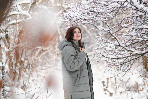 pretty woman in winter clothes among trees covered with snow, girl walking in snowy forest enjoying beautiful nature
