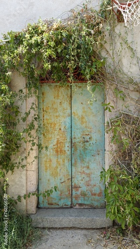 The door with metal swings of an ancient abandoned house in the countryside.